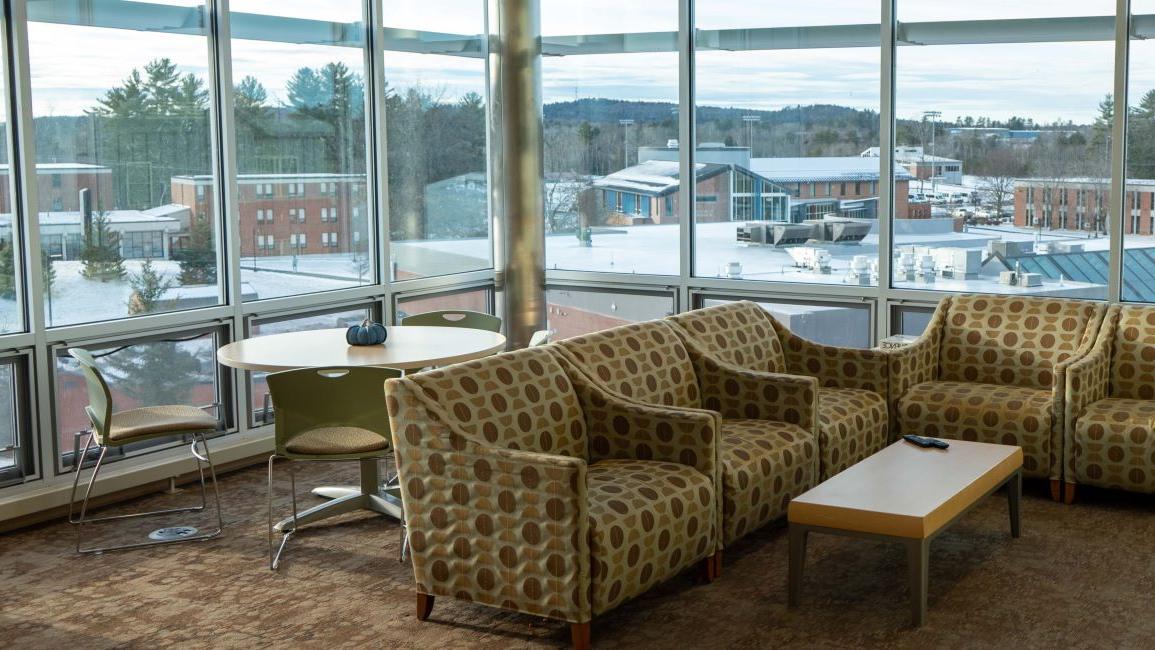 Polka-dotted couch near round table and chairs in front of a window with a view of campus