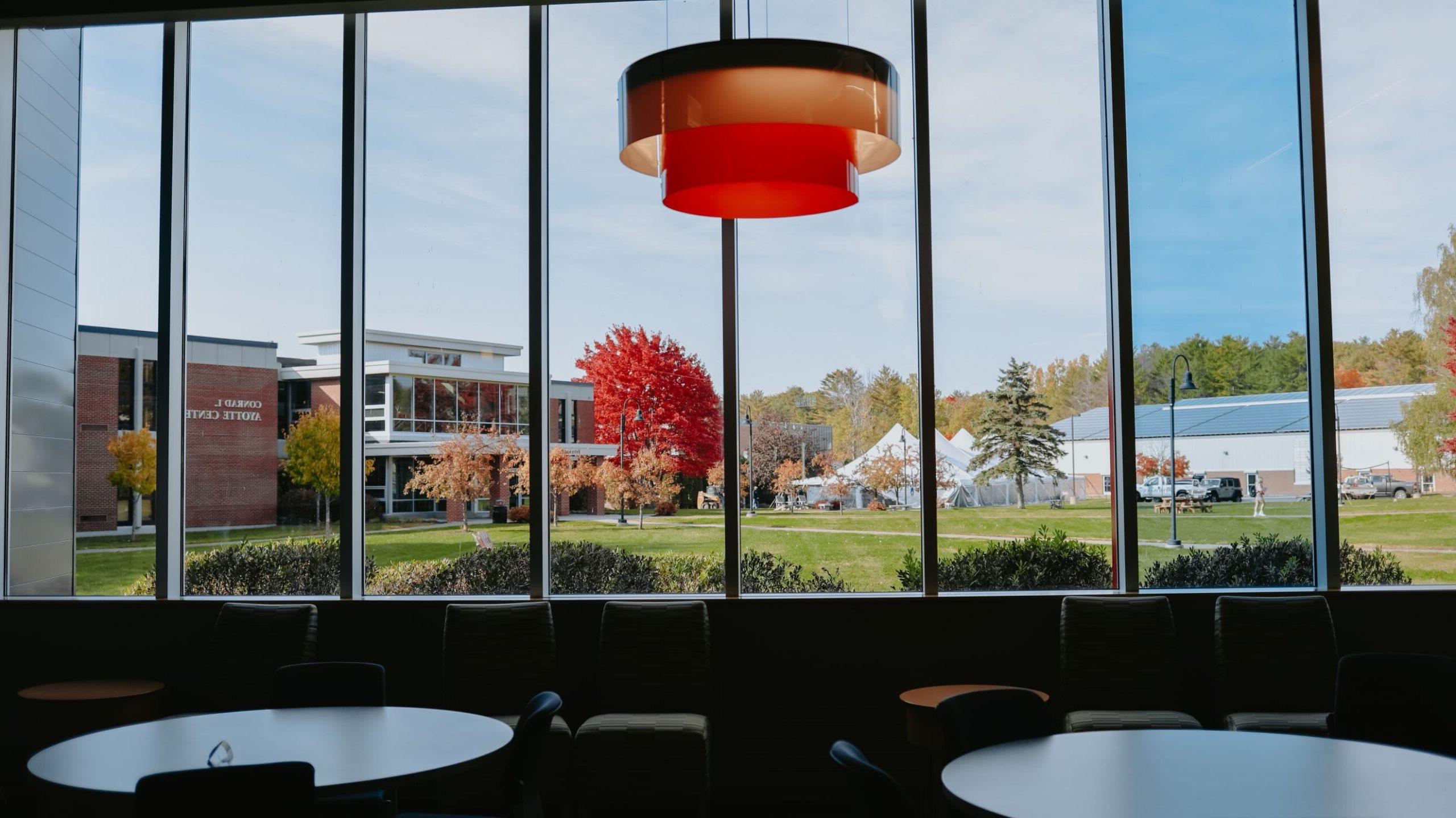View through a large window overlooking Thomas College quad and Ayotte Center.